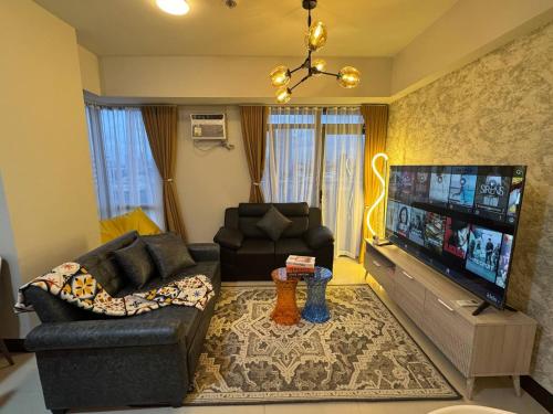 a living room with a couch and a flat screen tv at Modern Spacious 2BR 68 sqm Condo in Manhattan Heights Pool View in Manila