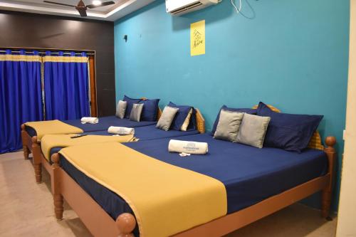 three beds in a room with blue and yellow at Aishwaryam home stay in Madurai