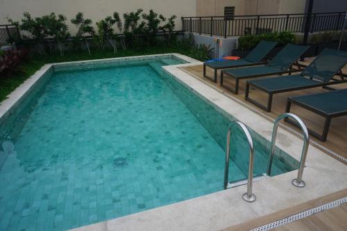 a large swimming pool with chairs in a building at Studio Aconchegante in Sao Paulo