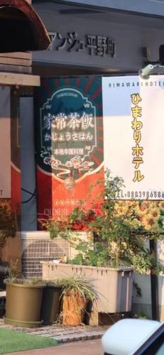 a sign on the side of a building with plants at ひまわりHotel in Nagasaki