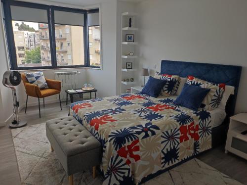 a bedroom with a bed and a chair and a window at Alojamento Local Mariposa Azul in Valença