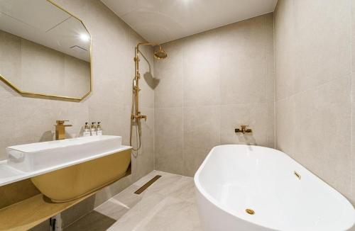 a bathroom with a white tub and a sink at Munhyeon Signature Denbasta Hotel in Busan