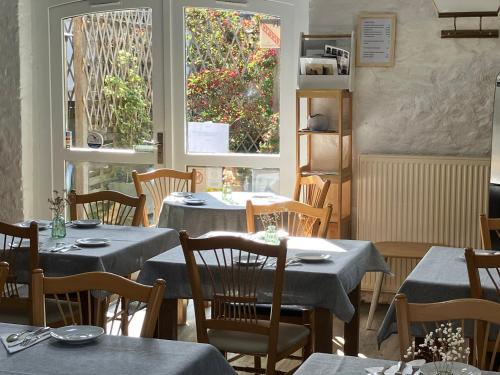 a restaurant with tables and chairs and two windows at Logis Hôtel La Demeure du Perron in Quettehou