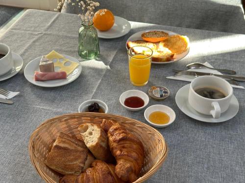 a table with a basket of croissants and coffee and orange juice at Logis Hôtel La Demeure du Perron in Quettehou