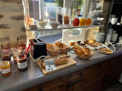 a buffet with bread and pastries on a counter at Logis Hôtel La Demeure du Perron in Quettehou