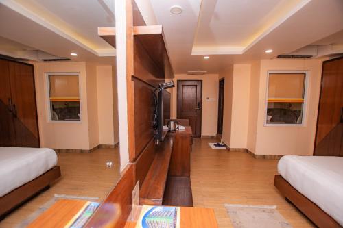 a room with two beds and a tv on a wall at Hotel Yellow Pagoda Pokhara in Pokhara