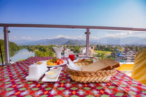 a table with a plate of food on a table with a view at Hotel Yellow Pagoda Pokhara in Pokhara