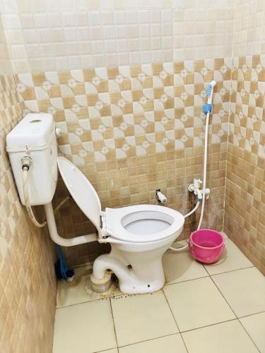 a bathroom with a toilet with a pink bucket at Kanak Bihari Yatri Niwas, 100 Meter Ram Ki Paidi, Saryu River in Ayodhya