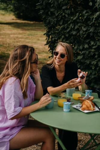 two women sitting at a table eating food at Les Roulottes & Cottages du Moulin in Chenillé-Changé
