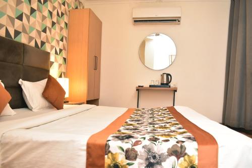 a hotel room with a bed and a mirror at Qotel Comfort Chattarpur - Opposite Tivoli Garden Near Chattarpur Metro in New Delhi