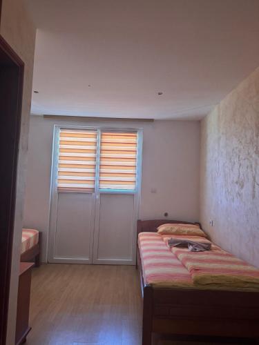 a bedroom with a bed and a door with a window at Guest House Ethno Village Milogora in Pluzine