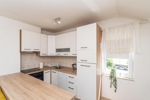 a kitchen with white cabinets and a window at Apartment Majer in Mokošica