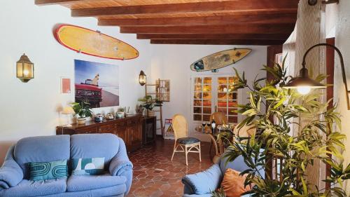 a living room with a blue couch and surfboards on the wall at Coastal Garden Paradise Retreat- 6 min from the beach in Charneca