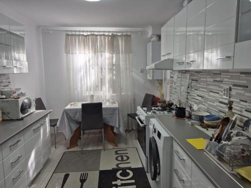 a kitchen with white cabinets and a table in it at Tulcea Soft Apartment in Tulcea