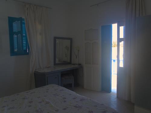 a bedroom with a bed and a mirror and a door at Family Home in Midoun