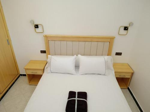 a bed with two white pillows and a black bag on it at Stay with dkouk 2 in Akchour