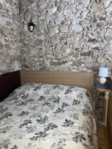 a bed in a room with a stone wall at Castell de Tati in Platja  d'Aro