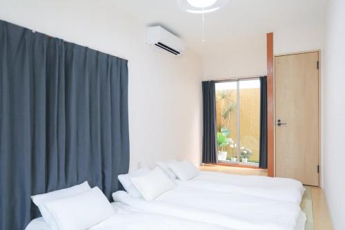 two white beds in a room with a window at 花の宿 in Osaka
