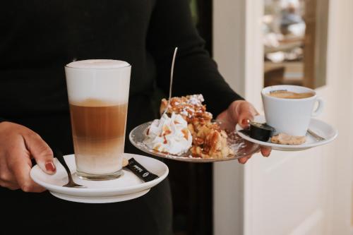 a person holding a plate of food and a cup of coffee at Sevenster Delden in Delden