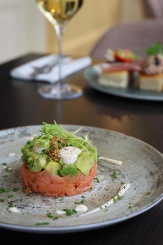 a plate with a sandwich on a table with a glass of wine at Sevenster Delden in Delden