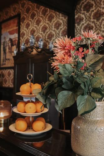 a table with three plates of oranges and a vase with flowers at Sevenster Delden in Delden