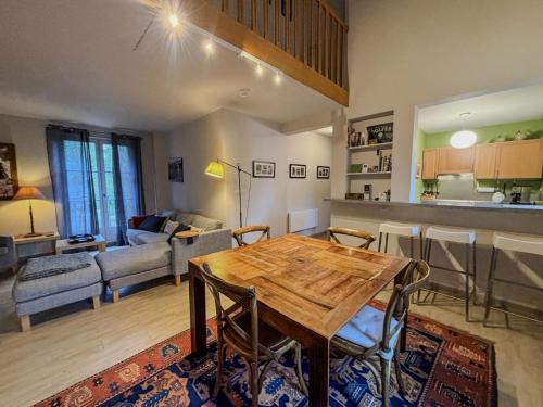 a kitchen and living room with a wooden table and chairs at Joli T3 au pied du Golf - The 19th Hole in Bellême