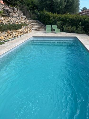 - une piscine avec 2 chaises vertes dans l'établissement Hauteurs de Toulon : Charmant studio piscine, à Toulon