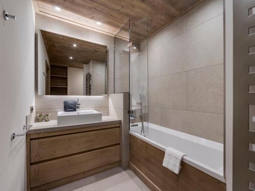 une salle de bain avec un lavabo, une baignoire et un miroir dans l'établissement Bel appartement 4 pièces avec terrasse et parking, à 350m du centre de Val d'Isère - FR-1-567-40, à Val dʼIsère