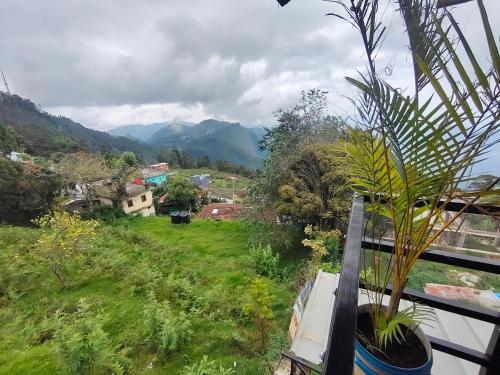 a balcony with a view of a field and mountains at MISBHA HomeStay in Kodaikānāl