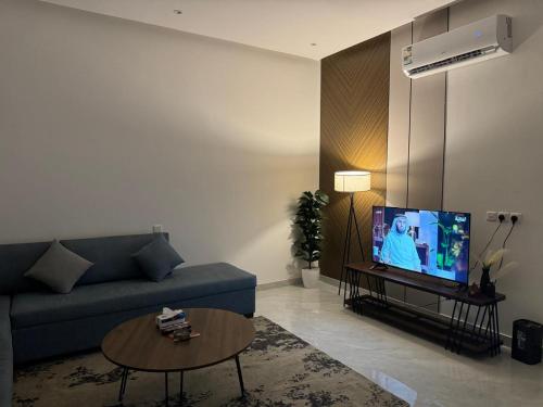 a living room with a blue couch and a tv at شقق الدانة وصول ذاتي in Hafr Al Baten