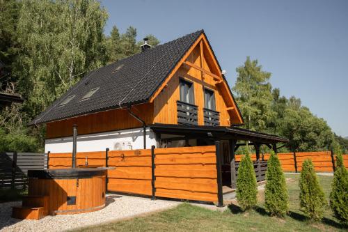a cabin with a black roof and a wooden fence at Chaty ForRest in Valča