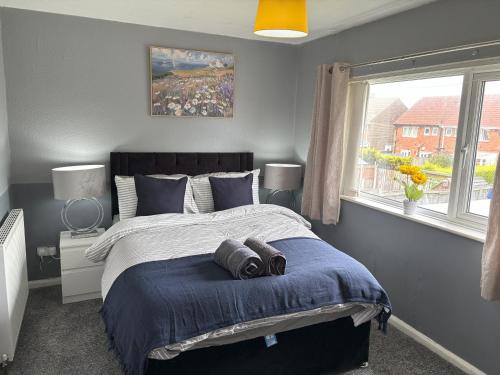 a bedroom with a bed with blue sheets and a window at Zinoc Abode Free Parking in Cowpen