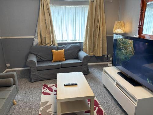 a living room with a couch and a flat screen tv at Zinoc Abode Free Parking in Cowpen