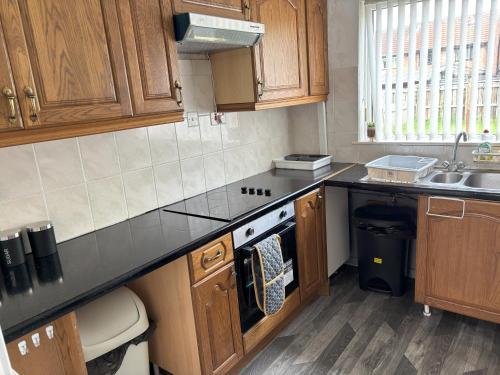 a kitchen with a sink and a stove top oven at Zinoc Abode Free Parking in Cowpen