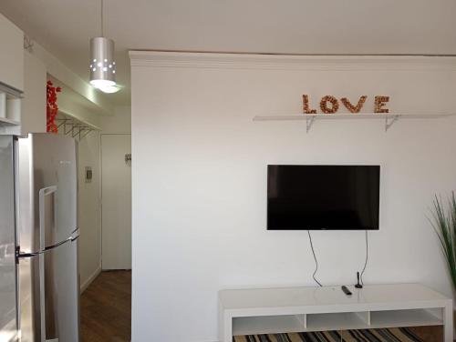 a living room with a tv on a white wall at Aconchego house in Sao Paulo