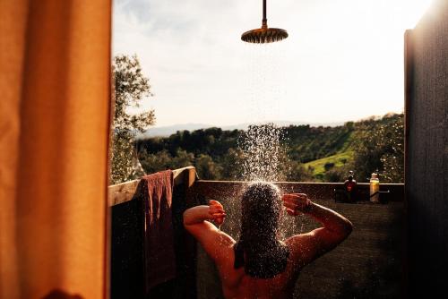 a man standing in a pool spraying himself with water at Tepee - Glamping Maremma, Toscana in Roccastrada