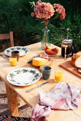 a wooden table with plates of food and a vase of flowers at Tepee - Glamping Maremma, Toscana in Roccastrada