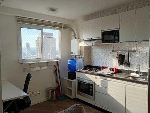 a kitchen with white cabinets and a stove top oven at Aconchego house in Sao Paulo