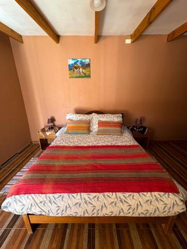 a bedroom with a large bed with a red blanket at Hostal Hara in San Pedro de Atacama