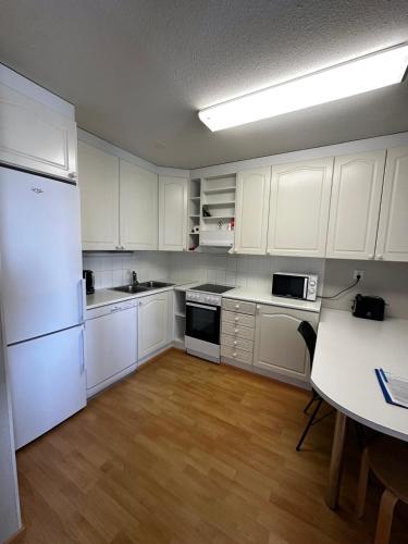 a kitchen with white cabinets and a table and a refrigerator at Jääskän Loma Ratatie 3 asunto 6 Kauhava in Kauhava