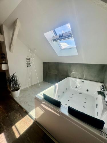 a bathroom with a bath tub with a skylight at Comfort Jacuzzi New Apartment in Nilvange in Nilvange