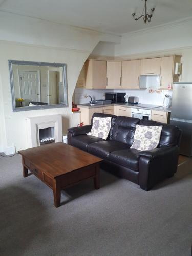 a living room with a black leather couch and a coffee table at Manhattan Lodge in Lytham St Annes