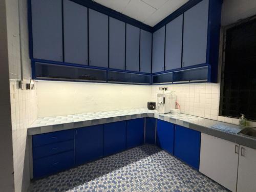 a blue kitchen with blue cabinets and a microwave at White House - Alor Setar in Alor Setar