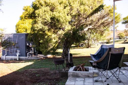 a group of chairs and a tree in a yard at Tranquility Glamping in Winterton