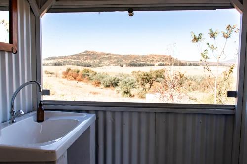 a bathroom with a sink and a large window at Tranquility Glamping in Winterton