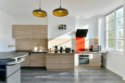una cocina con armarios de madera y una gran ventana en Spacieux Centre-ville Balcon, en Saint-Étienne