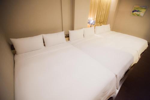 a large white bed with white pillows in a room at Kaishen Sinsu Hotel in Taitung City
