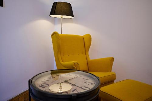 a yellow chair and a clock and a lamp at Apartmán Mariánská-centrum in Liberec