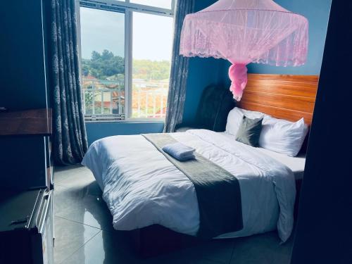 a bedroom with a bed with a pink item on it at Elly Villa Hotel in Moshi