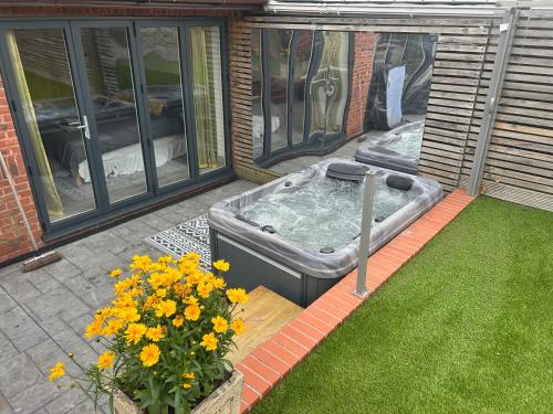 a hot tub sitting on a patio with flowers at The Quarry Woolton Village in Childwall